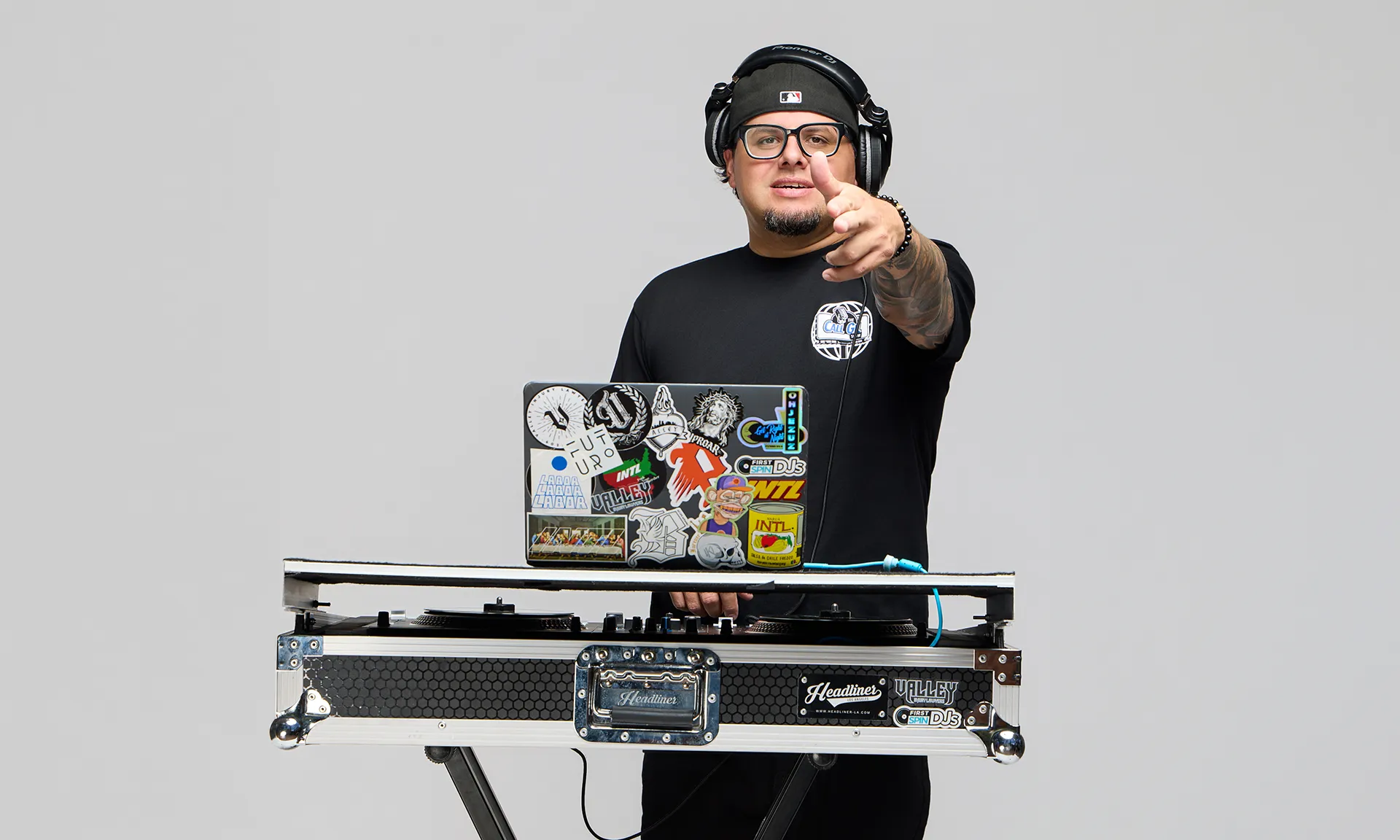 Jezuz Standing pointing behind his djing equipment